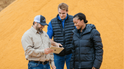 Three people viewing an tablet at a granary.