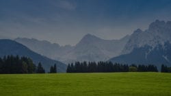 Field with woods and mountains in the background.