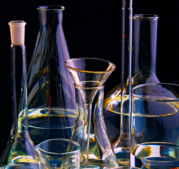 Various glass beakers with a dark background.