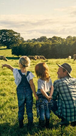 Dad with two daughters look out over a field.