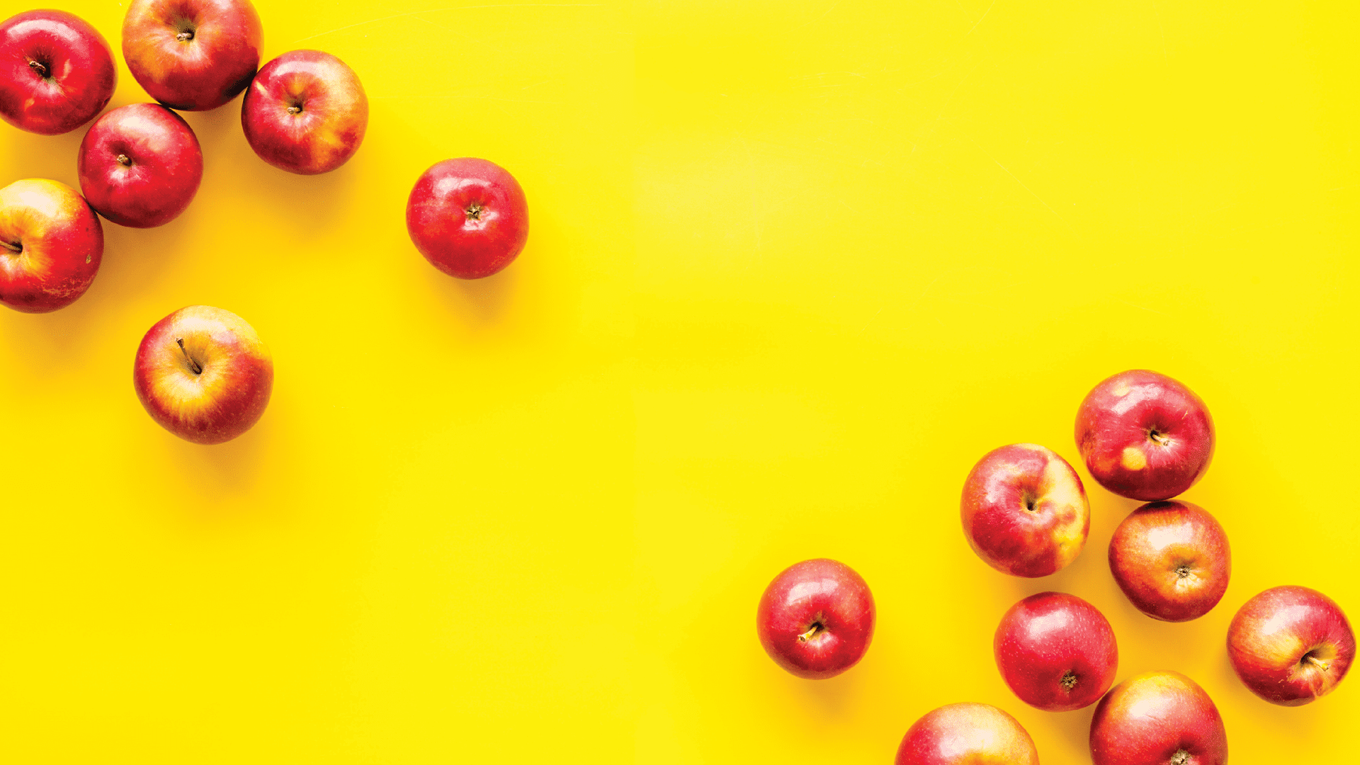 Apples scattered on a yellow background.
