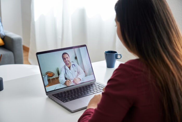 A lady using her laptop for a video appointment with her doctor
