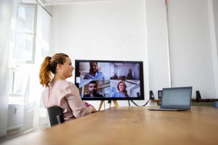 Businesswoman sitting on conference room and having online meeting with team. Business team meeting over internet.