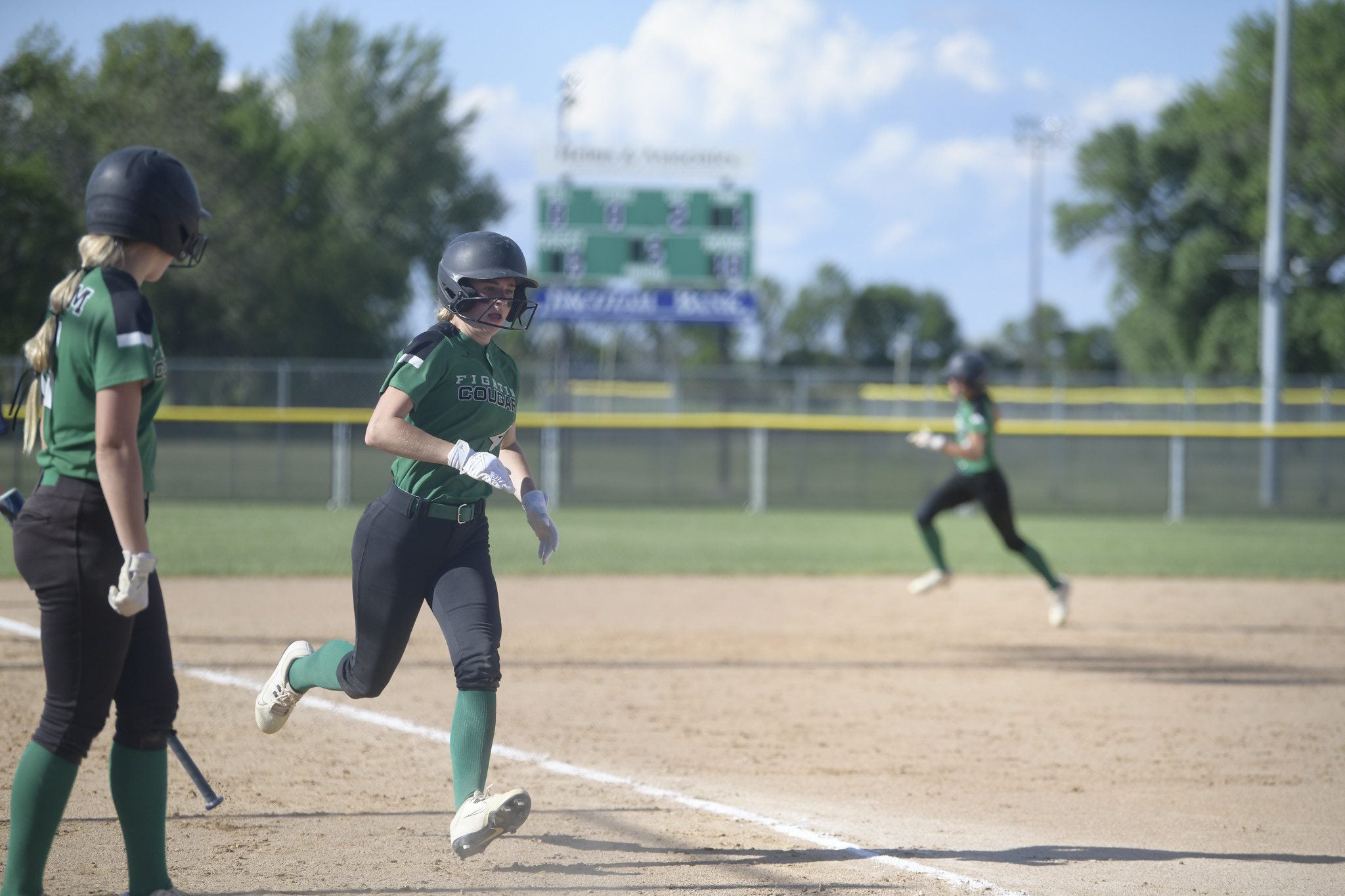 This is an image of a softball game with a player running the bases.